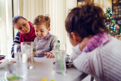 Boy using smart phone while sitting with women at home