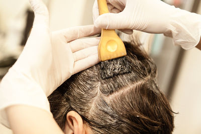 Cropped hands of barber coloring woman hair