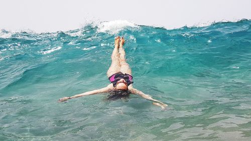 Full length of carefree woman with arms outstretched swimming in sea