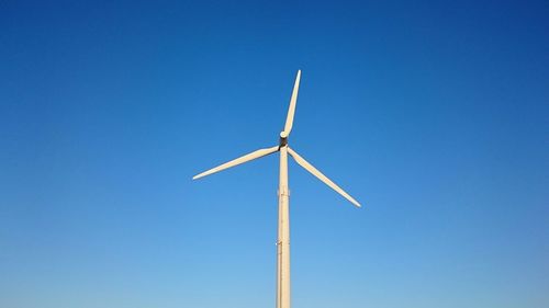 Low angle view of windmill against clear blue sky