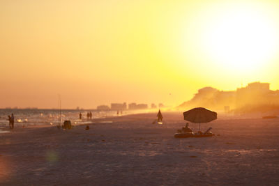 Silhouette people on beach against sky during sunset