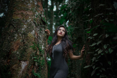 Woman looking away while standing in forest