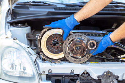 Automotive technician holding used car clutch disc, pressure plate and release bearing