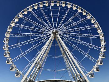 Low angle view of ferris wheel against blue sky