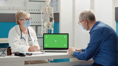 Doctor showing laptop screen to patient at clinic