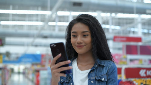 Young woman using mobile phone in supermarket