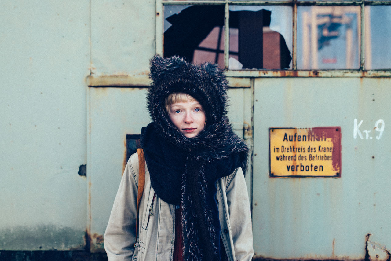 Portrait of woman standing against wall