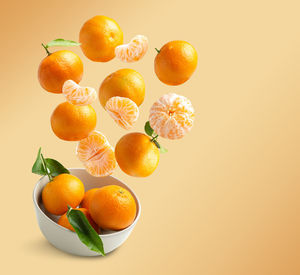 Tangerines flying isolated from orange background with copy spac