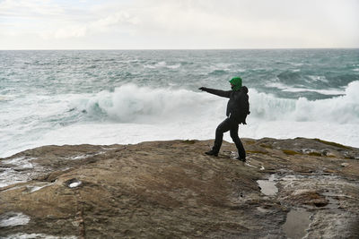 Full length of man standing at sea shore against sky