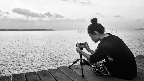 Woman photographing sea against sky