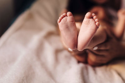 Cropped image of of mother holding baby feet at home