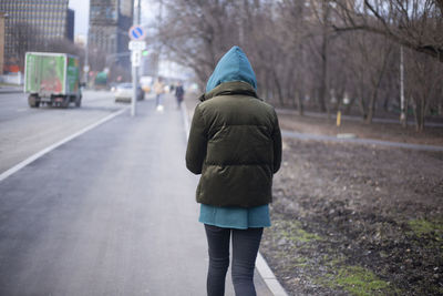 Rear view of woman walking on street in winter