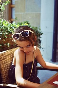 Portrait of young woman wearing sunglasses sitting outdoors