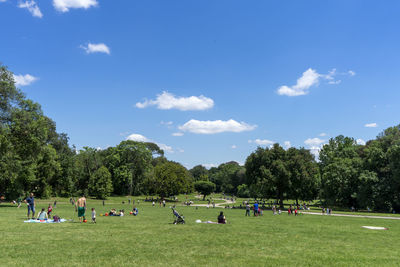 Group of people playing soccer on field against sky