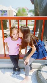 Girl kissing on sister cheek in balcony