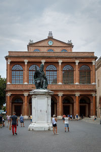 People in front of historical building against sky