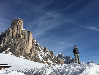 Low angle view of man standing on snow covered mountain against sky