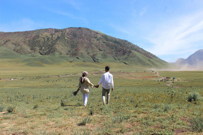 Rear view of people on landscape against sky