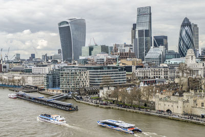 Modern buildings by river against sky in city