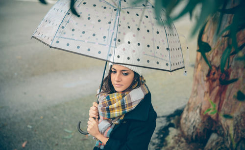 Portrait of woman with umbrella standing in rain