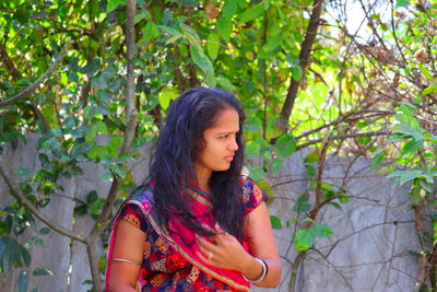 A portrait of a young asian girl standing in the open hairs in a garden nearby rock standing nearby