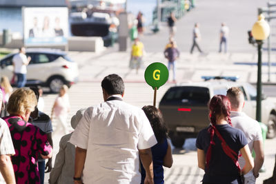 Rear view of people walking on road in city