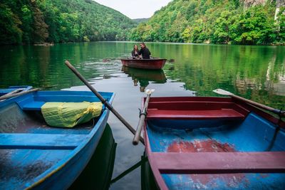 Friends sitting in boat on lake against mountains