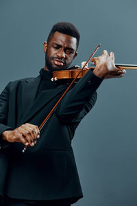 Young woman holding violin against blue background