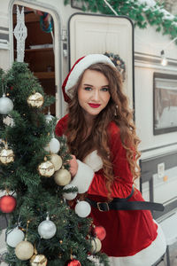 Portrait of smiling young woman standing against christmas