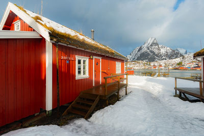 Building by snowcapped mountain against sky during winter