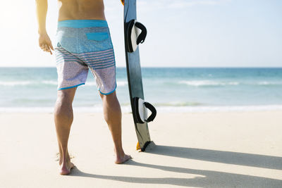 Low section of man standing on beach