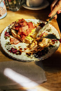 Hand of woman cutting food with knife at table