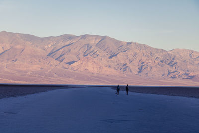 Distant view of female friends on road against mountains