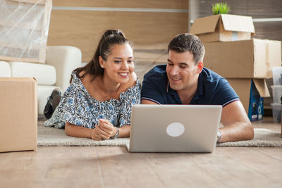 Portrait of smiling young woman using laptop at home