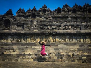 Full length of woman jumping against temple