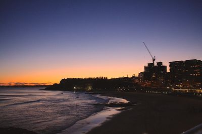 Scenic view of beach against clear sky at sunset