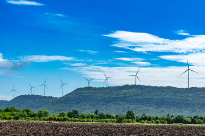 Wind turbines on field against sky