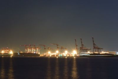 Illuminated harbor by sea against sky at night