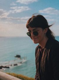 Woman wearing sunglasses at beach against sky
