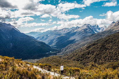 Rear view of woman looking at mountains against sky