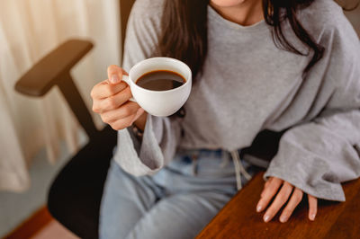 Midsection of woman having coffee at desk