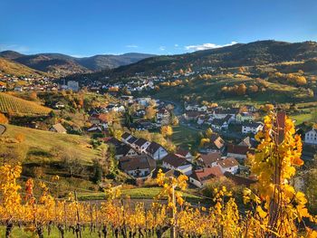 Scenic view of field by houses against sky during autumn