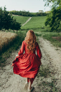 Rear view of woman walking on pathway in the countryside