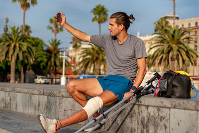 Young latin man with crutches taking a selfie after doing exercise