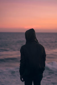 Rear view of silhouette man looking at sea during sunset