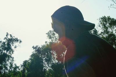 Close-up of silhouette man holding umbrella against sky