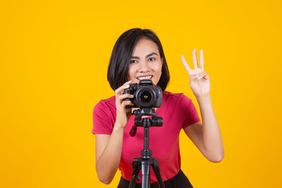 Portrait of smiling man photographing against yellow background