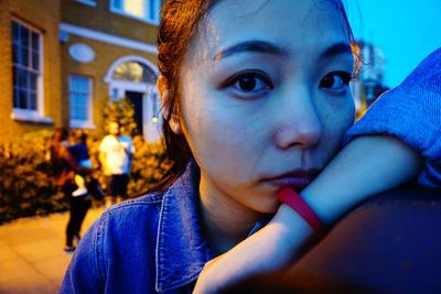 Close-up portrait of woman against house