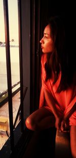 Woman looking away while sitting by window