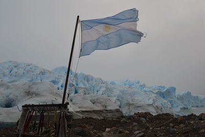 Flag on snow covered mountain against sky